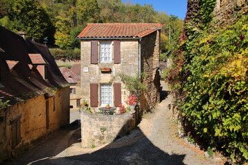 Traditional medieval houses with sloping slate roofs in the village Beynac et Cazenac, Dordogne, France, blend into a magnificent cliff