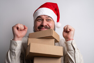 Happy man in santa hat holding stack of delivery boxes