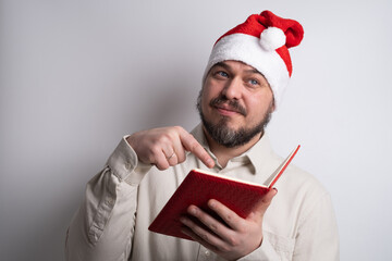 Man in santa hat pointing to red notebook