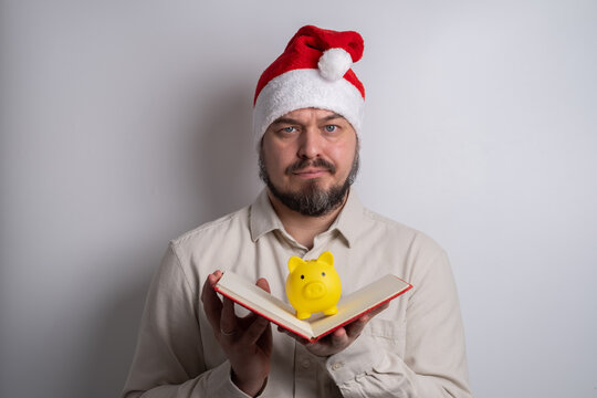 Man in santa hat holding piggy bank in notebook