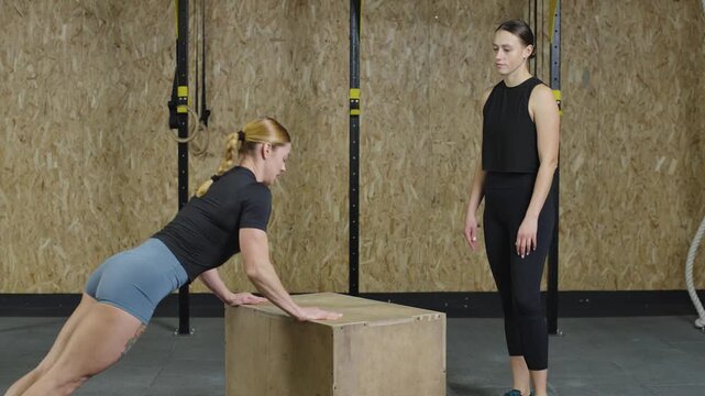 Athletes demonstrate slow motion push-ups and box jumps in a gym setting for strength training and fitness improvement