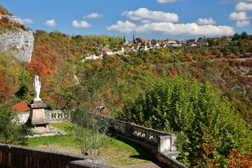 View from the village Rocamadour, lot, France, towards the hamlet l'Hospitalet, with Autumn colors and the statue of Saint Martial (unveiled in 1896) in the foreground 