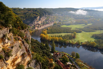 The river Dordogne and the village La Roque Gageac, Dordogne, France, viewed from Marqueyssac with spectacular cliffs, Autum colors and morning mist