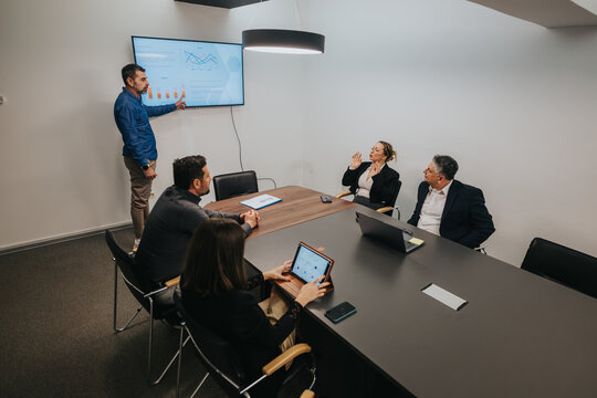 Team of professionals conducting a presentation and discussing data analysis in a well-lit meeting room. - Powered by Adobe