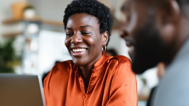Two professionals share a joyful moment in a contemporary office setting. Their laughter fills the air as they discuss ideas. The friendly atmosphere enhances teamwork