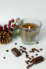 burning candle in coffee beans on a background of a Christmas tree branch with a cone