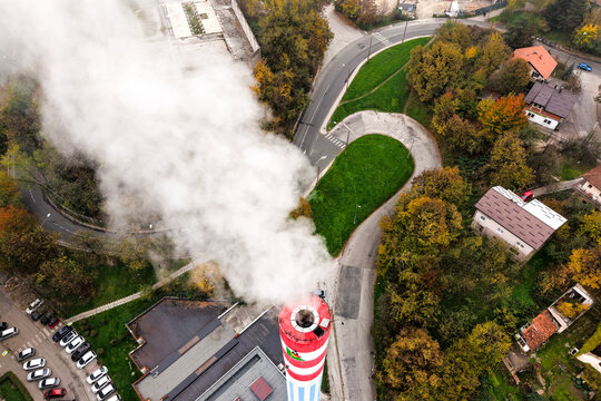 Aerial view of a towering smokestack billowing white smoke against a backdrop of autumn foliage and winding roads, Sarajevo, Federation of Bosnia and Herzegovina, Bosnia and Herzegovina.