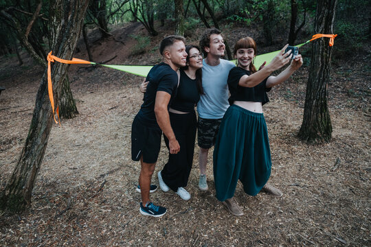 A quartet of friends poses for a cheerful selfie in a wooded area, sharing a fun moment during an outdoor outing. Laughter and smiles convey friendship, adventure, and casual fitness.