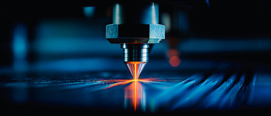 Laser cutting machine in operation with bright orange light on a metallic surface in a dark space