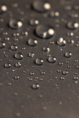 a black surface covered with water drops, details of the wet part of an object made of black plastic