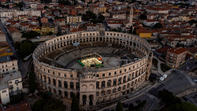 Pula, Croatia - 17 November 2025: Aerial view of the ancient Roman amphitheater, bathed in the soft glow of twilight, stands as a majestic testament to history amidst the modern cityscape.