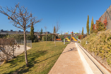 Inclusive play area with a wheelchair-accessible swing and spring rocker, in a public garden with colorful, continuous rubber flooring