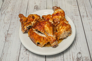 Half a traditionally roasted chicken with its own caramelized juices, served on a bed of roasted onions and accompanied by corn on the cob and glazed carrots