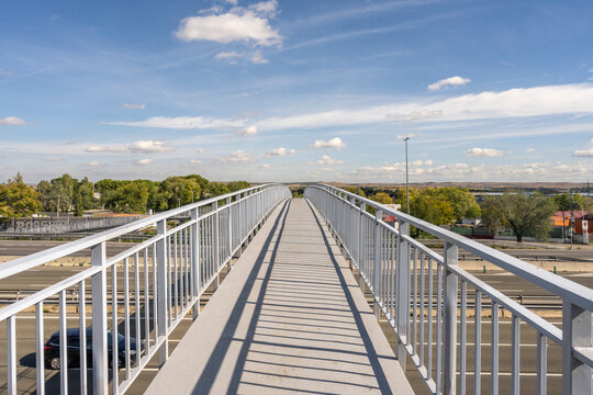 The architectural solitude of the white metal footbridge is accentuated by its complete emptiness, creating a minimalist and futuristic backdrop above the flow of traffic