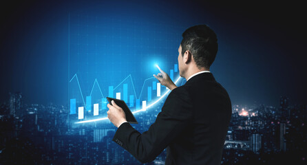 A businessman in a formal suit analyzes financial data with digital graphs displayed against a night urban skyline, symbolizing growth and innovation. Impute