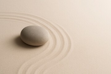 Obraz premium Smooth zen stone on fine beige sand with raked circles and space for text, minimalistic and peaceful concept for mindfulness meditation balance and calm visuals