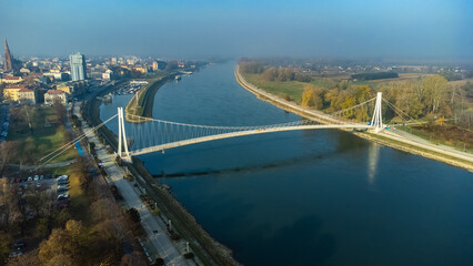 Aerial view of the striking white pedestrian bridge elegantly spanning the tranquil Drava River near the historic cathedral, Osijek, Osijek-Baranja County, Croatia.