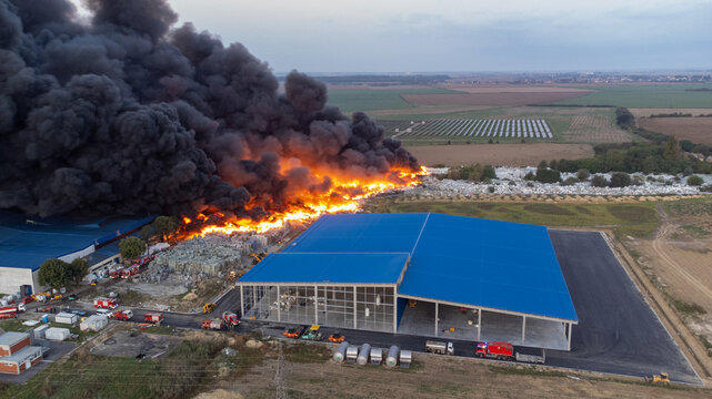 Aerial view of billowing black smoke and fierce orange flames engulfing a building near the open fields, Osijek, Osijek-Baranja County, Croatia.