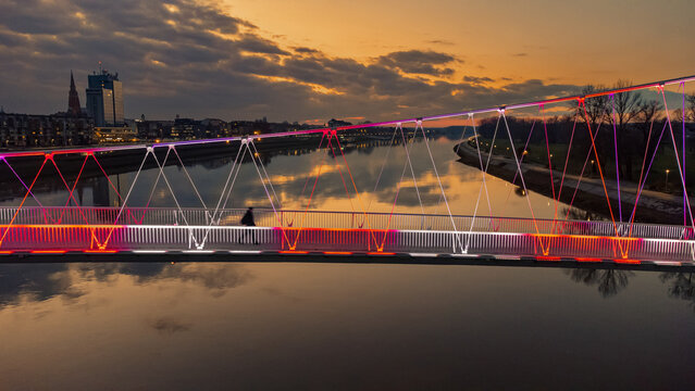 Aerial view of a bridge reflecting the vibrant sunset over the Drava River, with the distant cathedral spires, Osijek, Osijek-Baranja County, Croatia.