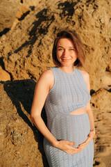 Pregnant woman smiling at camera by the rocks