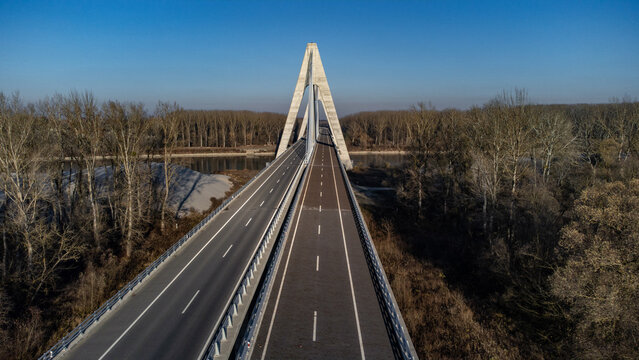 Aerial view of the sleek, modern Ante Starcević Bridge cuts a striking figure against the backdrop of the Drava River and autumnal forests, Osijek, Osijek-Baranja County, Croatia.