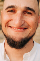 Close-up portrait of smiling man with beard and freckles
