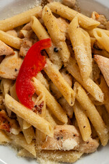 alfredo chicken pasta,Alfredo sauce with cooked penne rigate pasta in creamy sauce and juicy chicken in white plate.Top view.