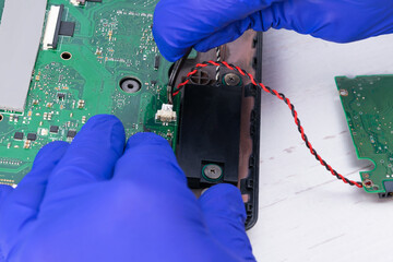 The master's hands connect the phone's display to a power source, close-up