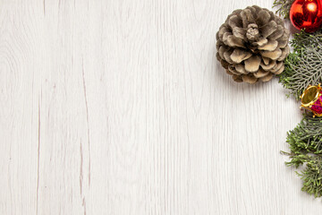 Christmas holiday decor with pine cone and red baubles on a light weathered white wood