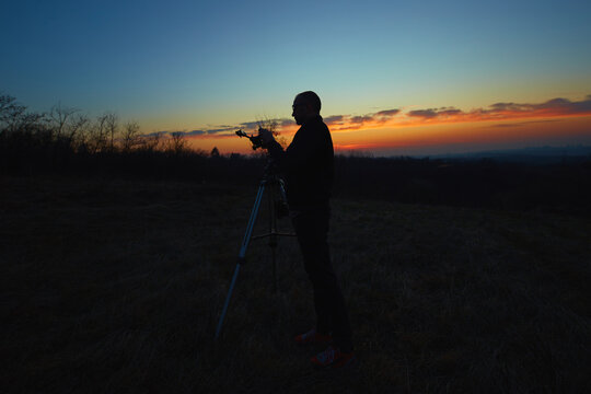 Amateur astronomer using telescope for watching stars, Moon, planets and other celestial objects from a field in nature.