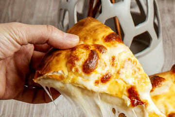 Hand Lifting a Cheesy Slice of Hot Khachapuri Bread with Cheese Pull
