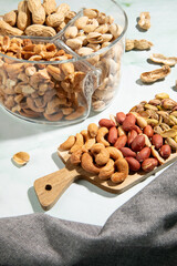 Dried fruits cashews, peanuts and pistachios on kitchen countertop.