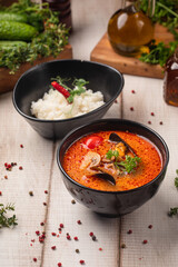 Aromatic spicy tom yam soup with mussels shrimp mushrooms and herbs paired with rice bowl