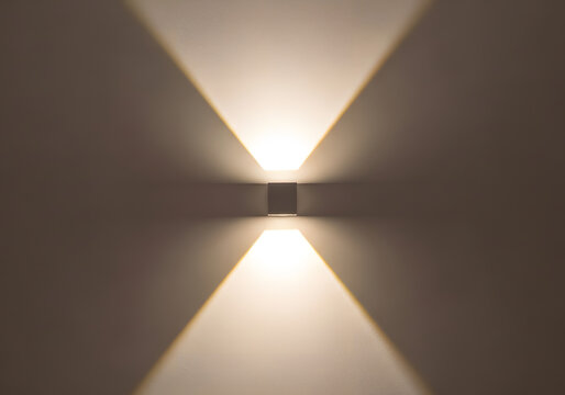 Modern wall light fixture casting upward and downward beams of illumination