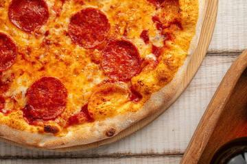 Hot pepperoni pizza with tomato sauce and melted cheese served on a wooden board