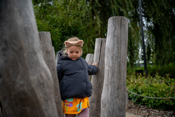 Active lifestyle and outdoor activity for children. Little girl on a wooden obstacle course on an autumn day.