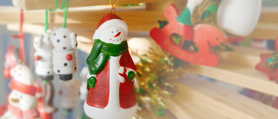 Décoration de Noël d'un bonhomme de neige et autres figurines en bois, accrochés à une branche de sapin fait maison à partir de planches en bois, format bannière