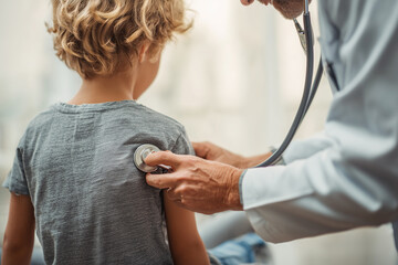Doctor listening to child’s breathing during routine pediatric exam