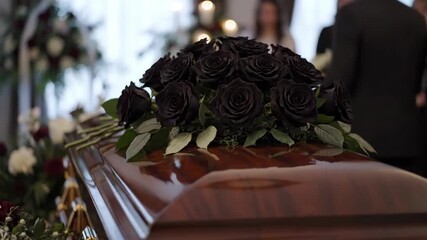 Funeral ceremony with black roses arrangement on a wooden coffin. Respectful farewell service honoring lost loved one. Memorial event, remembrance concept.