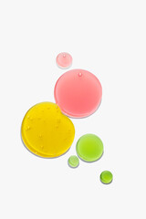 Swatches of round drops of yellow, green and red shower gel on a white background