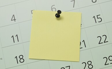 A blank yellow reminder pinned to a calendar page