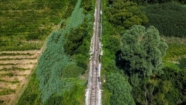 Aerial view of a railway track after a derailment through a vibrant green landscape, with people walking along the tracks, Velika Ludina, Sisacko-moslavacka zupanija, Croatia.