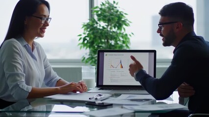 Business colleagues collaborate, viewing financial data on a laptop, discussing graphs and charts - Powered by Adobe