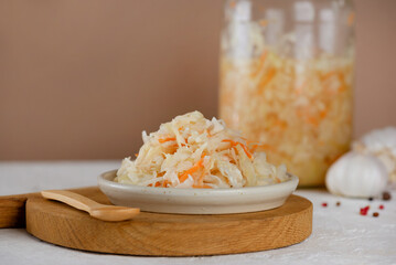 Fresh sauerkraut, pickled cabbage with carrot, pepper and garlic on a wooden board.