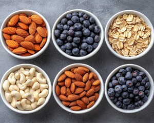 Six white bowls contain blueberries, almonds, cashews, & oats. Showcase healthy ingredients for cereal, snack or food concepts.