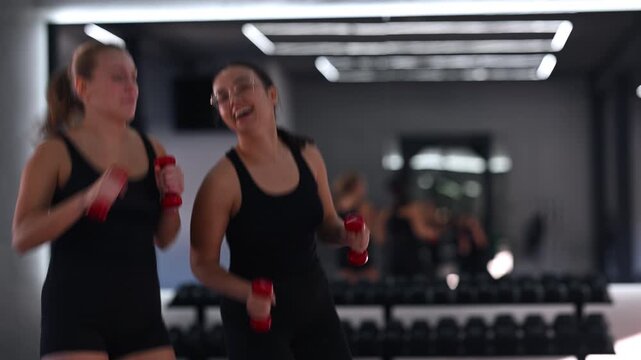 Women enjoying a fun workout together with dumbbells in a bright gym environment