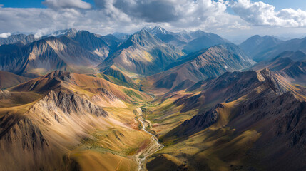 Aerial view of a valley with a winding river surrounded by mountains under a cloudy sky