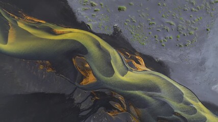 Aerial view of stunning braided river with yellow and dark color tones flowing through the landscape, creating intricate patterns, Grindavikurbaer, Iceland.