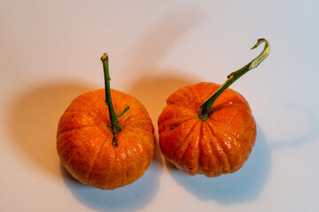 Two fresh ripe tangerines with stems on white