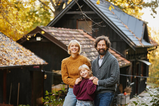 A joyful family stands together outdoors, surrounded by vibrant autumn leaves. They share smiles and laughter, showcasing a moment of love and connection during a weekend getaway.